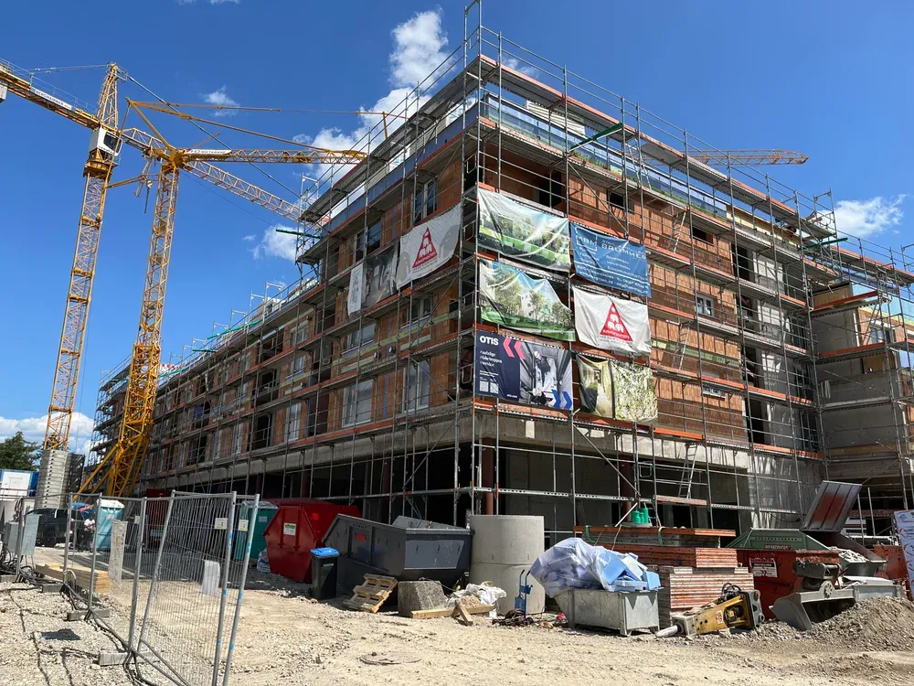 Rohbau-Fassade mit Gerüst, Bannern und Kränen